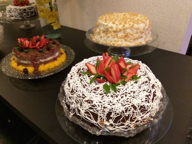 Mesa com tres tipos de torta doce confeitadas com morangos