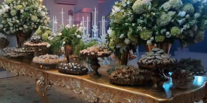 Mesa de doces suntuosa com dois arrajos de flores brancas