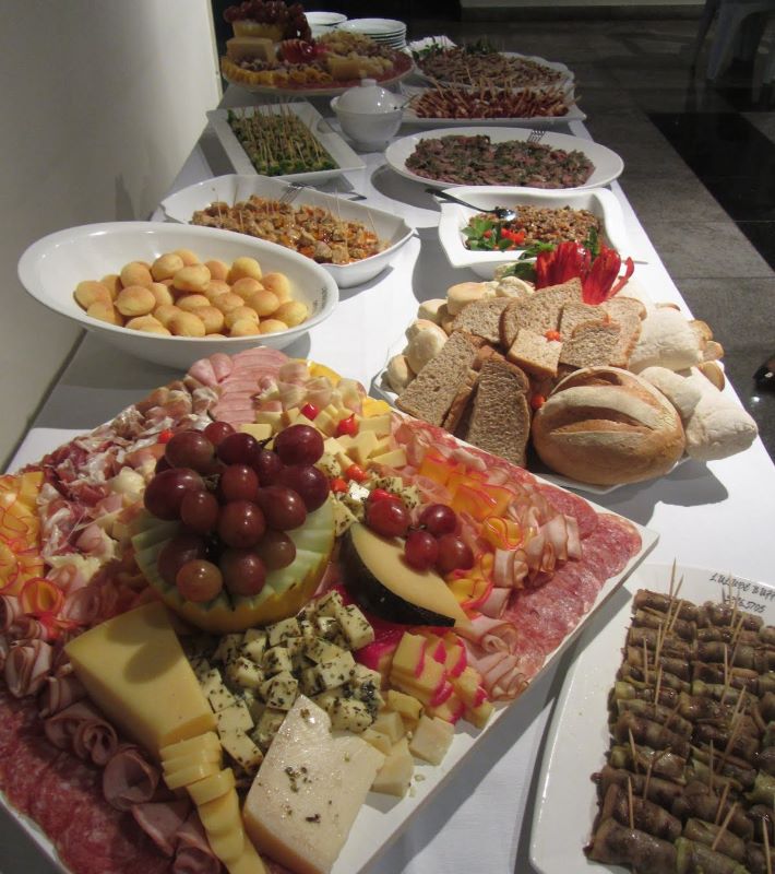 Mesa com paes, pao de queijo, pastas e frios