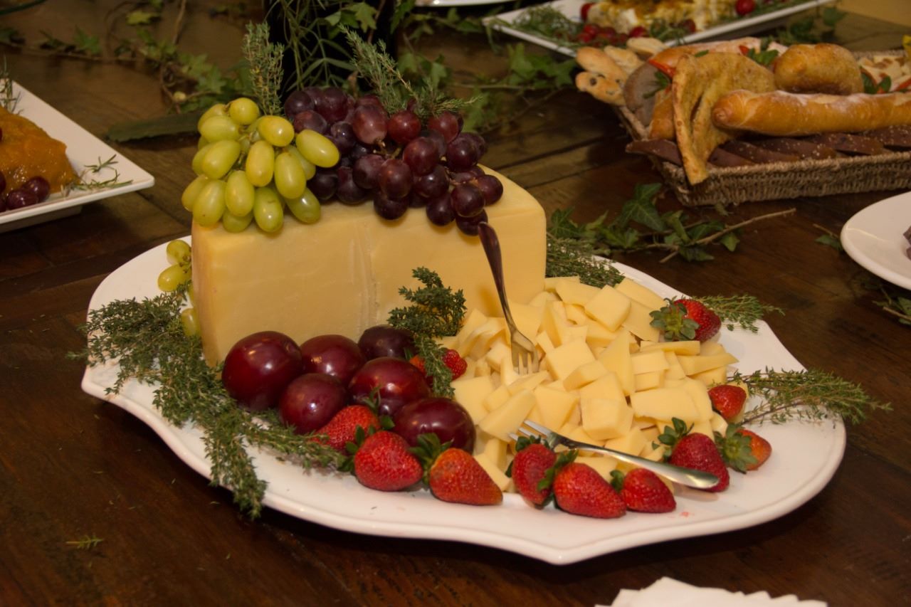 Prato com queijo fatiado decorado com uvas e morango